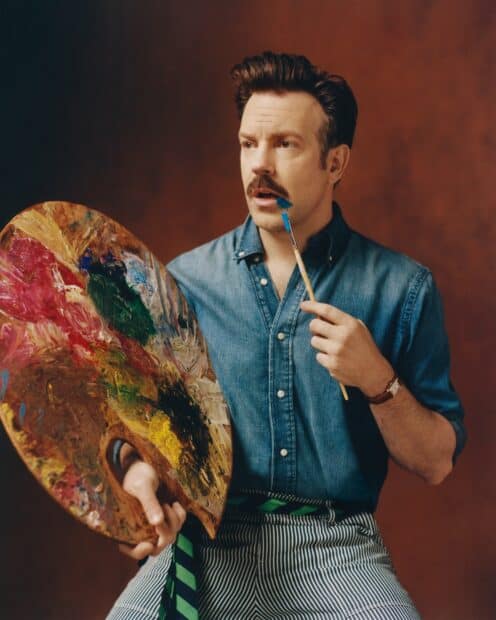 Jason Sudeikis is holding a colorful painter palette and a paintbrush with blue paint near his face, HD Phone Wallpaper