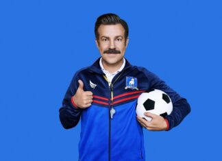 Jason Sudeikis is wearing a blue sports jacket and holding a soccer ball while giving a thumbs up, HD Desktop Wallpaper