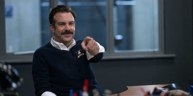 Jason Sudeikis is pointing forward with a friendly smile in an indoor setting, 2K Desktop Wallpaper