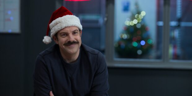 Jason Sudeikis wearing a Santa hat and smiling with a Christmas tree in the background, 2K Desktop Wallpaper