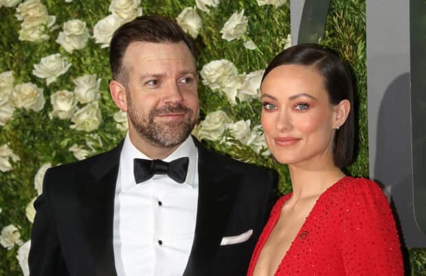 Jason Sudeikis standing beside a woman wearing a red dress at an event with floral decoration, 2K Desktop Wallpaper