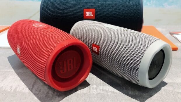 Red and gray JBL portable speakers placed on a table with a black JBL speaker behind, HD Desktop Wallpaper