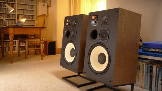 A pair of Jbl speakers placed on stands in a cozy room with wooden furniture and books, HD Desktop Wallpaper