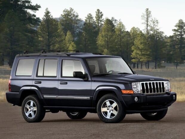 A black Jeep Commander SUV parked on a paved surface with pine trees in the background, HD Desktop Wallpaper