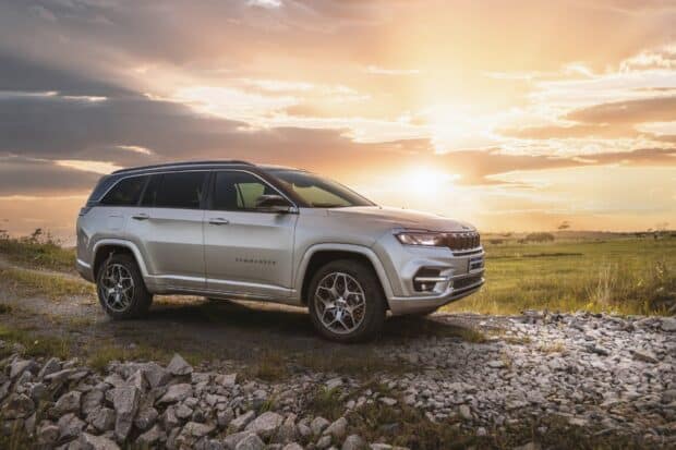 A Jeep Commander drives across rocky terrain during sunset in the countryside, HD Desktop Wallpaper
