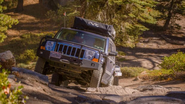 A Jeep Commander is navigating a rugged off road path surrounded by trees, HD Desktop Wallpaper