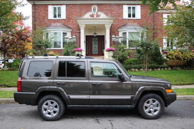 A Jeep Commander is parked on the street near a brick house with white columns and garden, HD Desktop Wallpaper