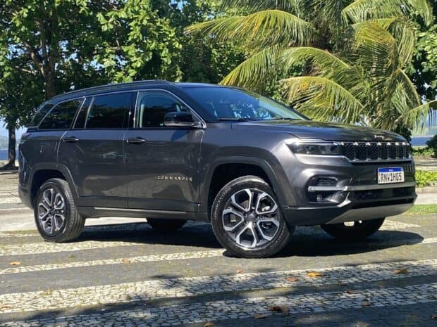 A sleek Jeep Commander is parked on a patterned pavement with palm trees in the background, 2K Desktop Wallpaper