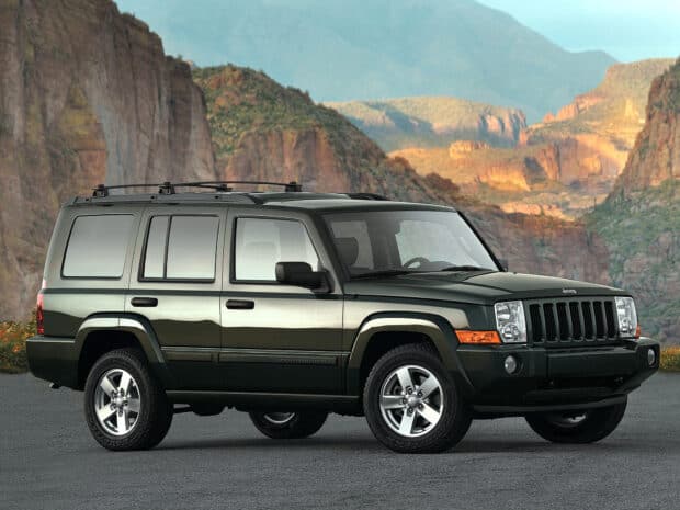 A dark green Jeep Commander is parked on a road with canyon cliffs in the background, HD Desktop Wallpaper