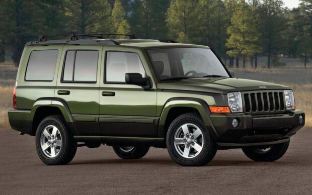 A green Jeep Commander is parked on a paved surface with trees in the background, 2K Desktop Wallpaper