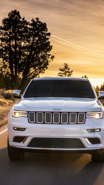 A white Jeep Grand Cherokee is shown driving down a road surrounded by trees during sunset, HD Phone Wallpaper