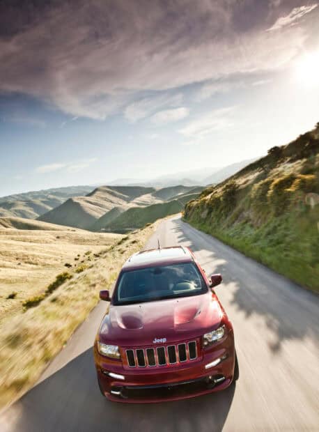 A Jeep Grand Cherokee drives along a winding road in the hills during the day, HD Mobile Wallpaper