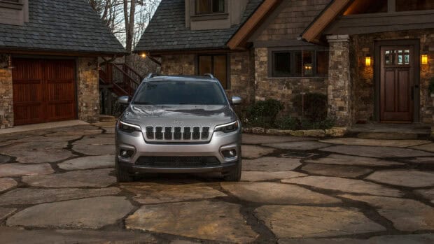A Jeep Grand Cherokee is parked in front of a stone house with a garage, 2K Desktop Wallpaper
