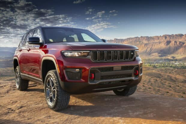 A red Jeep Grand Cherokee is parked on rocky terrain with mountains in the background, HD Desktop Wallpaper
