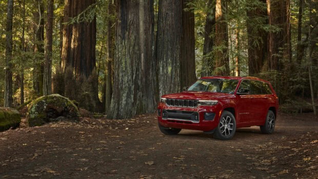 A red Jeep Grand Cherokee is parked among tall forest trees on a dirt path, HD Desktop Wallpaper