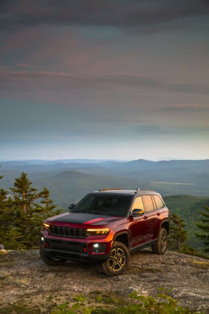 A Jeep Grand Cherokee is parked on a rocky hill with mountains in the background during sunset, 2K Mobile Wallpaper