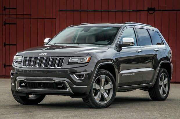 A gray Jeep Grand Cherokee is parked in front of a red barn wall showing its full side and front, HD Desktop Wallpaper