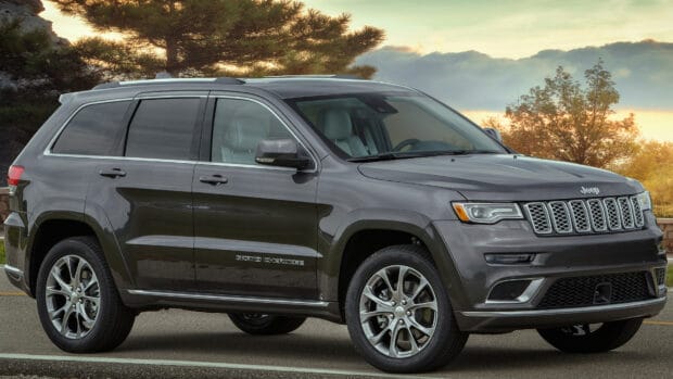 A Jeep Grand Cherokee is parked on the road with autumn trees in the background during sunset, 4K Desktop Wallpaper