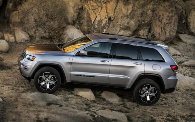 A silver Jeep Grand Cherokee parked on rocky terrain under sunlight, HD Desktop Wallpaper