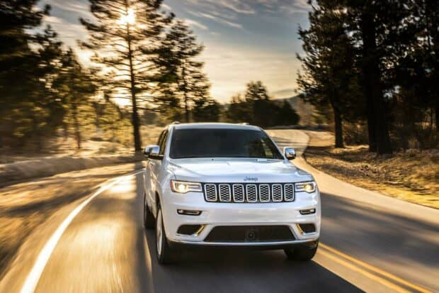 A white Jeep Grand Cherokee drives on a winding forest road during sunset, HD Desktop Wallpaper