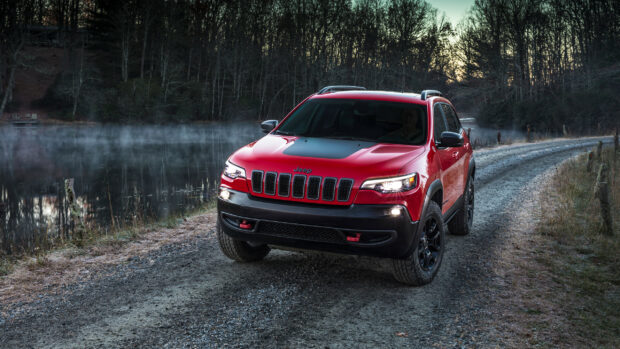 A red Jeep Grand Cherokee is parked on a foggy forest dirt road at dusk, 2K Desktop Wallpaper