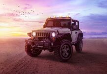 A Jeep is parked on a desert ground under a colorful sunset sky with birds flying, 4K Desktop Wallpaper