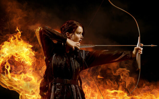 Jennifer Lawrence aims her bow and arrow surrounded by flames in a dramatic pose, 2K Desktop Wallpaper