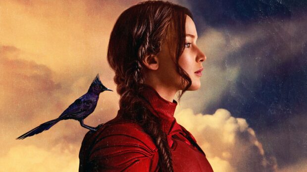 Jennifer Lawrence wears a red costume with a bird perched on her shoulder in The Hunger Games scene, 2K Desktop Wallpaper