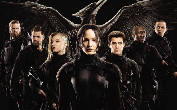 Jennifer Lawrence with the Hunger Games cast standing with a large bird symbol behind them, HD Desktop Wallpaper