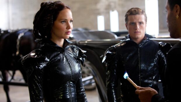 Jennifer Lawrence in a black outfit interacts with two men in a tense moment from The Hunger Games, HD Desktop Wallpaper