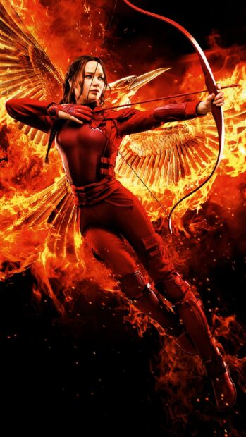 Jennifer Lawrence aiming her bow with fire and a golden bird symbol behind her in The Hunger Games, 2K Mobile Wallpaper