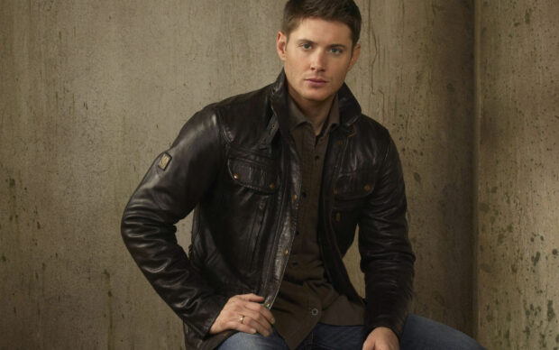 Jensen Ackles wearing a dark leather jacket posing against a concrete wall, 2K Desktop Wallpaper