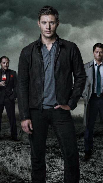 Jensen Ackles stands confidently with two men behind him under a cloudy sky, HD Phone Wallpaper