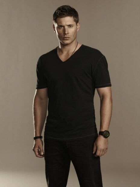 Jensen Ackles stands wearing a black shirt and jeans with a neutral background, HD Desktop Wallpaper