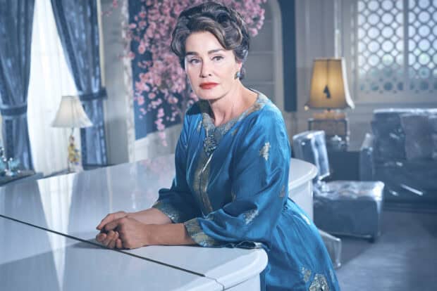 Jessica Lange wears a blue ornate dress sitting by a white piano in a decorated room, 2K Desktop Wallpaper
