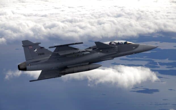 A jet fighter flying above the clouds with land visible below, 2K Desktop Wallpaper