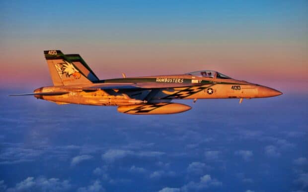 A jet fighter with Dambusters markings flies over clouds during sunset, HD Desktop Wallpaper