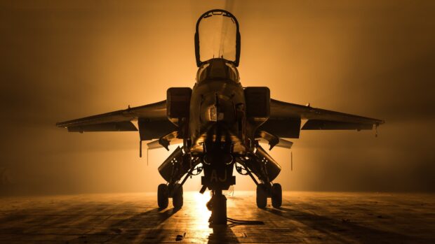 A jet fighter stands illuminated by golden lighting on the runway at night, 4K Desktop Wallpaper