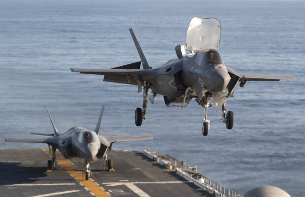A jet fighter is landing on an aircraft carrier over the ocean with another jet parked on the deck, HD Desktop Wallpaper