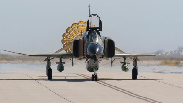 A jet fighter prepares to land on the runway with a braking parachute fully deployed behind it, HD Desktop Wallpaper