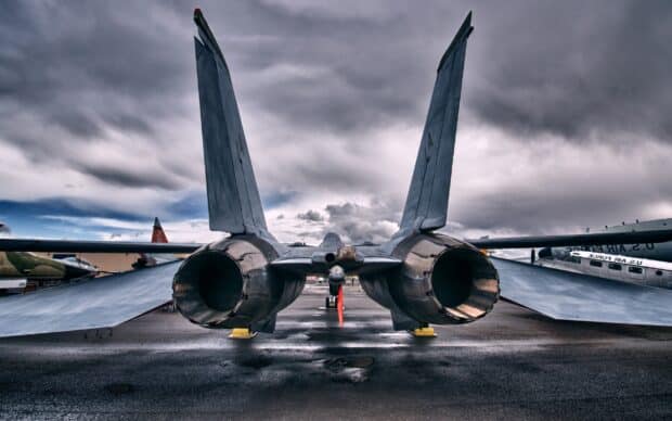 A jet fighter with open engine nozzles is parked on the airfield under a dramatic cloudy sky, 2K Desktop Wallpaper