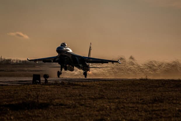 A jet fighter is taking off from a runway during sunset with heat waves visible behind it, HD Desktop Wallpaper