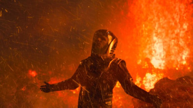 A character in armor stands with arms open amid flames and sparks in Jj Abrams setting, 4K Desktop Wallpaper