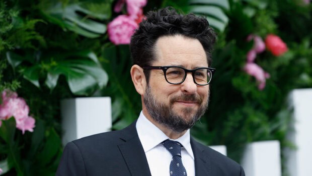 Jj Abrams in a suit smiling in front of a floral green backdrop, 2K Desktop Wallpaper