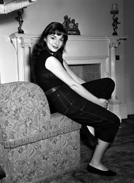 Joan Collins Wallpapers portrait sitting on patterned furniture by fireplace, 2K PC Wallpaper