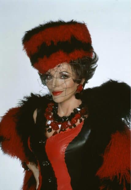 Joan Collins is dressed in a striking red and black fur outfit with matching jewelry and a netted hat, HD Mobile Wallpaper