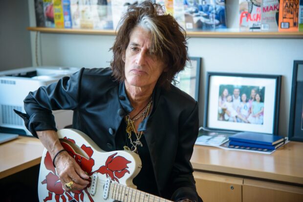 Joe Perry playing a white guitar with red designs while sitting indoors, HD Desktop Wallpaper