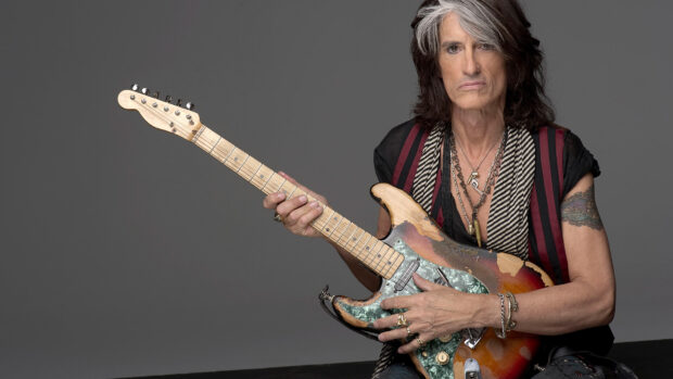 Joe Perry is holding a worn electric guitar with a serious expression, HD Desktop Wallpaper