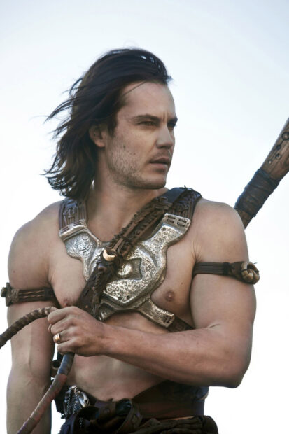 A muscular man is holding a weapon while wearing armor and looking into the distance in John Carter Wallpapers, HD Mobile Wallpaper
