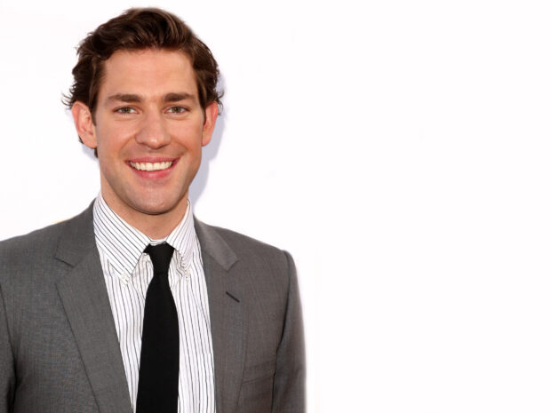 A close up portrait of John Krasinski smiling warmly in a gray suit and striped shirt, 2K Desktop Wallpaper